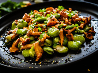 Broad beans salad with fried chanterelles, garlic and parsley on wooden table
