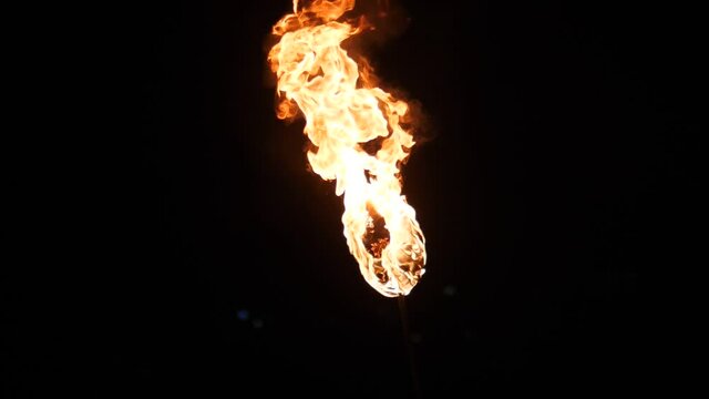 Round torch burn with long tongues of flame, black background, hand held shot. Light source and special effect at beach party during fire show, large ball wick soaked in fuel and burning