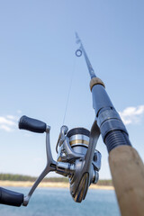 Fishing gear. Carbon fiber spinning rod on the shore of a lake. Hobby in nature.