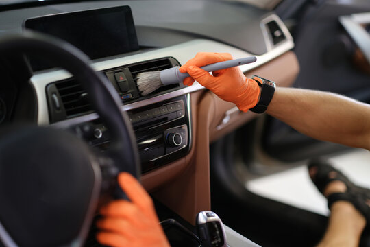 Male hand hold grey blush in orange protective gloves