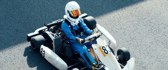 Teenager professional karting racer sits inside his go kart on a race track - obrazy, fototapety, plakaty