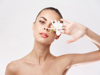 Obraz na płótnie Canvas woman with bare shoulders white flower cosmetics clean skin