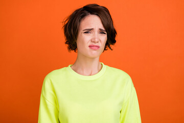 Photo of young brown bob haired unhappy stressed woman bad mood grimace isolated on orange color background