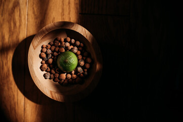 Overhead shot of a lime in a wooden bowl with clay pebbles - Powered by Adobe