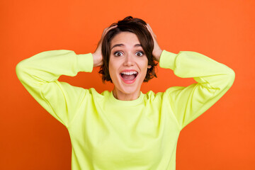 Portrait of attractive cheerful amazed lucky girl great news reaction isolated over bright orange color background