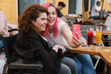 Young two women smiling and drinking Young three women taking selfie on cellphone while sitting in cafe while sitting in cafe