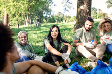 Multiethnic group of volunteers resting after cleaning city park.