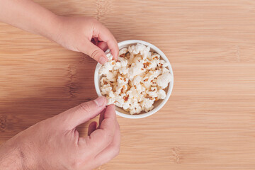 Father and son hands eating popcorn on a bamboo background