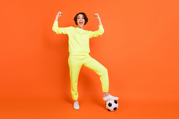Naklejka na ściany i meble Full length body size view of attractive lucky cheerful girl playing soccer rejoicing isolated over bright orange color background