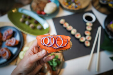 Carrot slices as fish substitute for smoked vegan salmon on whole wheat bread slices holding in hand