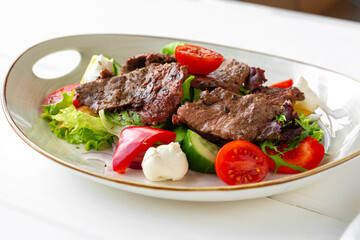 Fillet of beef with vegetable salad on wooden table
