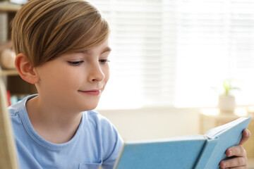 Fototapeta na wymiar Cute little boy reading book at home