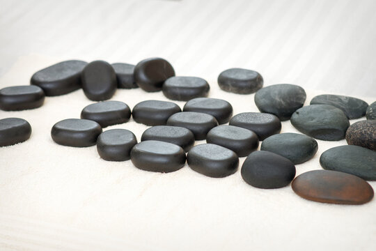 Many black massage stones lying isolated on the towel on the table