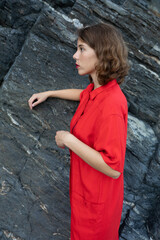 Stylish young woman in a vintage red dress of sixties lifestyle not looking at the camera 