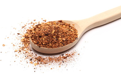Sliced red spicy pepper pile, chopped paprika in wooden spoon isolated on white background