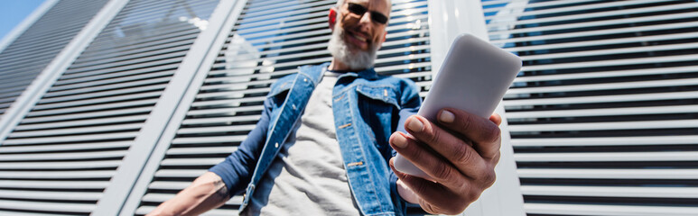 partial view of man holding smartphone outside