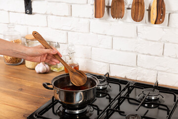 Woman cooks a soup in kitchen on gas plate