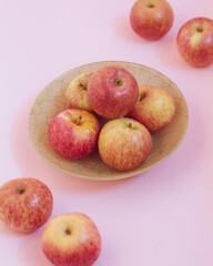 Fresh apples are lying in a green plate on a pink background
