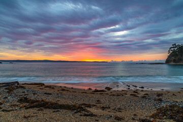 Obraz premium Cloud covered sunrise seascape tinged with pink