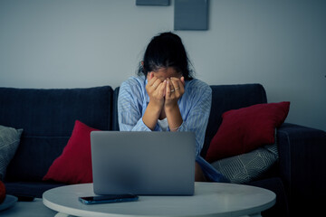 Young worried woman alone at home suffering from cyberbullying or blackmail.