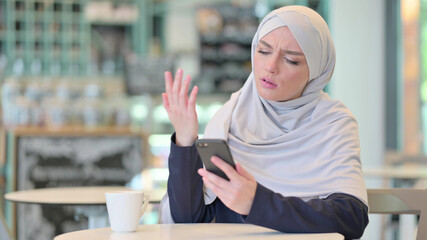 Disappointed Young Arab Woman having Loss on Smartphone 