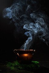 The witch's smoking cauldron on dark background.