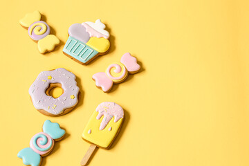 Colorful glazed gingerbread cookies on yellow background copy space.