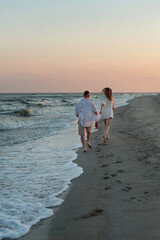 Fototapeta na wymiar happy beautiful couple walking at sunset along the seashore