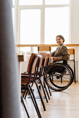 White woman in wheelchair smiling while having coffee break at office