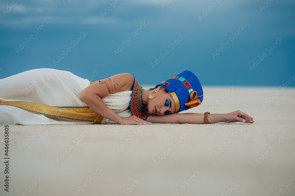 Wall mural woman in image of egyptian queen nefertiti lies on sandy in desert.