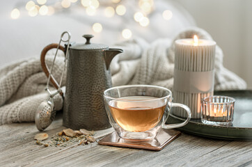 Cozy composition with a cup of tea, a teapot and candles.