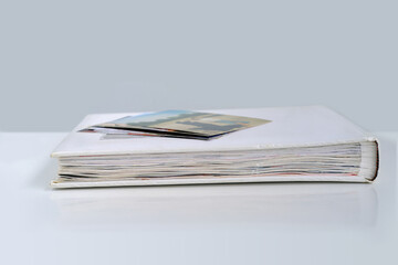 white photo album with photographs on a white table, side view, concept of genialogy tree, family...