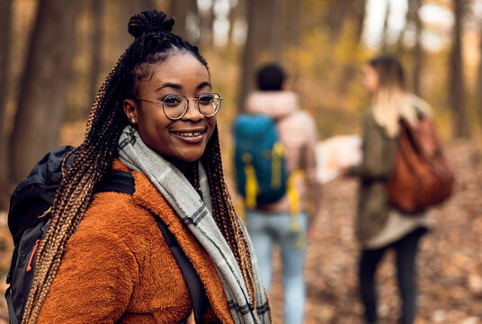 Portrait of young female hiker in forest with friends.
