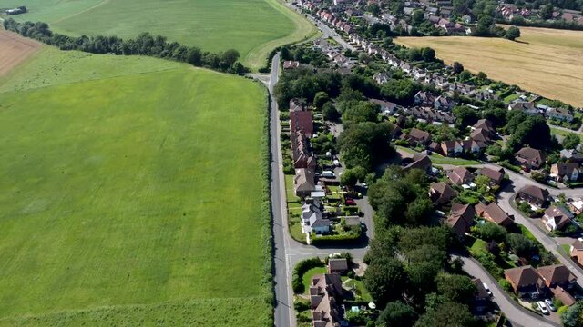 4K drone video showing a part of a housing estate with a road and farmland alongside