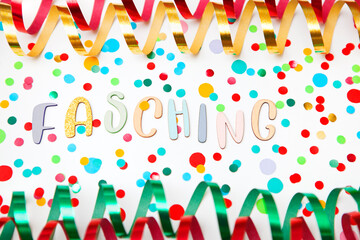 Colorful photo with letters of "Fasching", meaning carnival in German, paper streamers an confetti on white background.