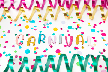 Colorful photo with letters of Carnival, paper streamers an confetti on white background.