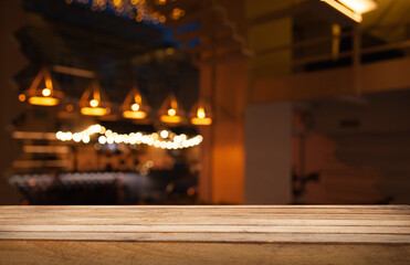 image of wooden table in front of abstract blurred background of restaurant, cafe, bar lights.