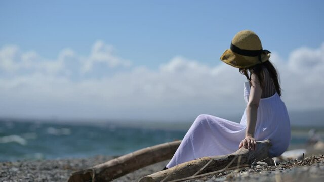 海岸に座る麦わら帽子をかぶった女性