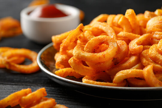 Golden Curly Fries with ketchup on rustic plate
