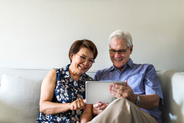 Senior couple in a living room using a digital device together