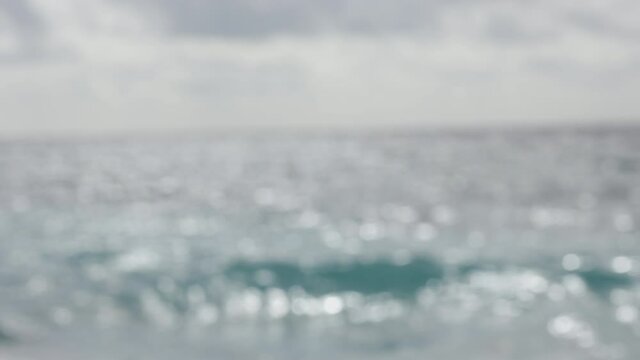 Defocused and blurred wavy sea water surface with a beautiful bokeh of sun glares and sparkls which are reflected from the ocean