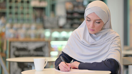 Serious Young Arab Woman Writing on Paper 