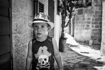Un niño con sombrero pasea por las calles de Polignano a Mare en Italia.