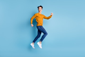 Fototapeta na wymiar Full body profile photo of impressed brunet millennial guy jump wear sweater jeans isolated on blue color background