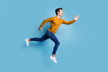 Fototapeta na wymiar Full length profile photo of funny brunet young guy run wear sweater jeans isolated on blue color background