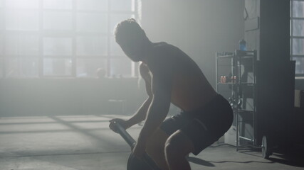 Fototapeta na wymiar Athlete finishing fitness workout with weights. Guy holding barbell in gym