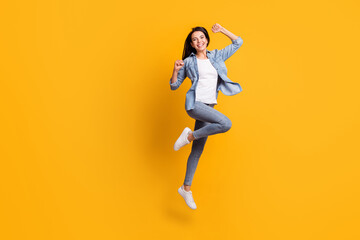 Fototapeta na wymiar Full size profile photo of cool hooray brunette lady run jump wear blue shirt jeans sneakers isolated on yellow background