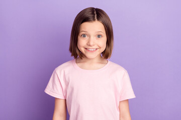 Portrait of attractive cheerful preteen girl wearing pink tshirt isolated over purple violet lilac color background