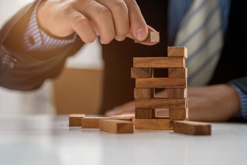 Close up hand of Business has piling up and stacking a wooden block.Businessman Building The Success,plan and strategy in business,risk concept.