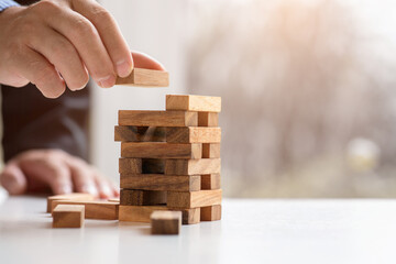 Close up hand of Business has piling up and stacking a wooden block.Businessman Building The Success,plan and strategy in business,risk concept.